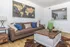 Contemporary living room with a cozy brown sofa, vibrant blue and patterned cushions, stylish wooden coffee table, and an elegant world map art piece adorning the wall.