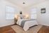 Bright and cozy bedroom featuring elegant decor, hardwood floors, and large windows with natural light.