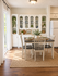 Charming dining space with elegant white cabinetry, vibrant greenery, and a cozy table set for four, bathed in natural light.