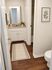 Elegant bathroom with warm wooden flooring, featuring a sleek vanity, modern fixtures, and stylish decor.