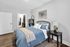 Cozy bedroom with plush bedding, modern artwork, and a stylish side table lamp.