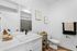 Chic bathroom with white vanity, black faucet, stylish decor, and contemporary artwork.