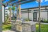 Spacious outdoor patio with a built-in grill surrounded by lush greenery and modern buildings.