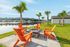 Vibrant outdoor patio with orange chairs and palm trees overlooking a serene lake.