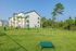 Spacious outdoor area of an apartment complex with a designated dog play park surrounded by lush greenery.