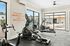 Modern gym with exercise machines and large windows showing a poolside view.