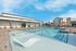 Luxurious outdoor pool with stylish lounge chairs and umbrellas at a modern apartment complex.