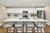 Modern kitchen featuring a sleek island with woven chairs, stainless steel appliances, and elegant white cabinetry.