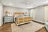 Elegant bedroom with a chic wicker bed frame, cozy blue accents, and stylish dual nightstands with lamps, set on warm wooden flooring.