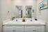 Elegant double vanity bathroom with chic white cabinetry, modern fixtures, and nautical-themed decor.