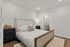 Elegant bedroom with a cozy wooden bed, nightstands, and a stylish table lamp, featuring modern minimalist decor in soft tones.