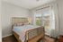 Bright and cozy bedroom with a charming wooden bed, elegant curtains, and warm natural light.