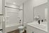Sleek and modern bathroom with elegant white tiles, luxurious bathtub, stylish vanity, and sophisticated black fixtures.