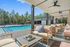 Luxurious outdoor lounge area by a pristine pool with elegant furnishings and scenic views of surrounding trees.