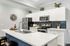 Sleek modern kitchen with white cabinetry, stainless steel appliances, and elegant blue tile backsplash, complemented by tasteful decor and a stylish clock.