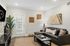 Charming living room with modern decor, featuring a plush gray sofa, elegant wall art, indoor plants, and ample natural light through glass doors.