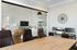 Modern home office with elegant glass wall, showcasing a stylish living room with sophisticated decor and warm wood finishes.