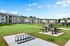 Inviting apartment complex with spacious green lawn, outdoor picnic area, and modern bike rack under a clear blue sky.