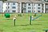 Spacious apartment complex with vibrant green pet-friendly play area, complete with agility equipment and comfortable seating.