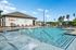 Inviting outdoor pool area with sun loungers and umbrellas, set against a backdrop of lush greenery and clear blue skies.