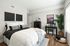 Chic modern bedroom with cozy white bedding, stylish black and gray accents, a sleek writing desk, and vibrant greenery, inviting natural light.