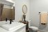 Elegant bathroom with modern fixtures, featuring a sleek white sink, stylish mirror, and decorative accents, creating a cozy and inviting atmosphere.