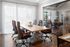 Elegant meeting room with sleek leather chairs around a wooden table, illuminated by natural light through sheer curtains and glass doors.
