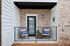 Charming brick apartment balcony with cozy seating, welcoming home pillows, and stylish decor.
