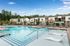 Luxurious apartment complex with a stunning outdoor pool, surrounded by modern townhouses and lush greenery, offering a serene and inviting atmosphere.