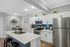 Modern kitchen with sleek white cabinets, stainless steel appliances, and a stylish island with barstools, ideal for a contemporary lifestyle.