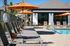Inviting apartment pool area with stylish lounge chairs and vibrant orange umbrellas under a clear blue sky.
