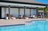 Inviting poolside area featuring cozy lounge chairs, stylish outdoor design, and tranquil surroundings for ultimate relaxation.