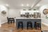 Modern open-concept kitchen with sleek white cabinets, stainless steel appliances, and elegant bar seating, complemented by cozy dining area and stylish decor.