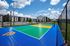 Inviting outdoor sports court with vibrant blue and green surfaces set against modern apartment buildings and a clear blue sky.