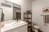 Modern bathroom featuring a sleek white vanity, stylish shelving with decor, and elegant fixtures for a luxurious feel.