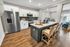 Modern kitchen with island, stainless steel appliances, and barstools.