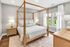 Spacious bedroom with natural light, neutral decor, queen-size bed, and modern furnishings.