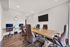 Elegant conference room with a wooden table, plush chairs, and floor-to-ceiling windows offering abundant natural light.