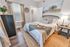 Inviting bedroom with modern decor, featuring a cozy white and cream bed, elegant wood furniture, and a fresh plant on top of a dresser