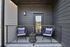 Charming outdoor patio with cozy seating, welcoming pillows, and lush greenery, perfect for relaxation and enjoying the fresh air.