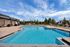 Resort-style pool featuring lounge bed chairs, clear blue water, and a relaxing outdoor setting.