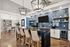 Elegant modern kitchen with a sleek tile backsplash, stylish open shelving, and plush bar seating, perfect for entertaining.