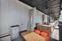 Elegant outdoor patio with plush seating, stylish cushions, and a vibrant orange mini-fridge, perfect for relaxed gatherings.