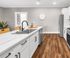 Modern kitchen with sleek white cabinets, elegant marble countertops, and stainless steel appliances, featuring a central island with a sink and stylish faucet.