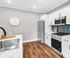 Modern kitchen with sleek white cabinets, stainless steel appliances, and elegant marble countertops, enhanced by a chic wall clock and stylish backsplash.