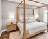 Inviting bedroom with elegant four-poster bed, warm wood accents, and soft lighting creating a serene retreat.