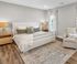 Elegant bedroom with a plush king-sized bed, cozy armchair, and stylish lamps, highlighted by soft, natural lighting and neutral d&eacute;cor.