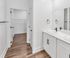 Elegant bathroom design with dual sinks, sleek fixtures, and a spacious walk-in closet with hardwood floors.