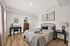 Elegant bedroom with a cozy bed, modern decor, and natural light pouring through large windows, creating a serene ambiance.