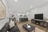 Inviting open-plan living room with plush leather couch, sleek kitchen island, and elegant dining area, perfect for modern comfort and style.